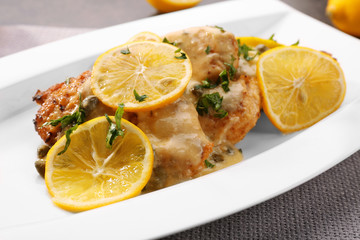Plate with tasty chicken piccata on table
