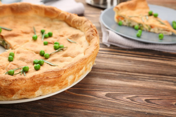 Tasty chicken pot pie with green peas on table