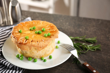 Tasty chicken pot pie with green peas on kitchen table