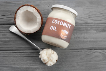 Spoon near glass jar with fresh coconut oil on grey wooden background