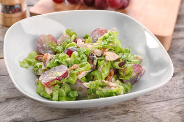 Plate with chicken salad and grapes on table