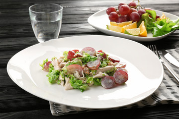 Plate with chicken salad and grapes on table