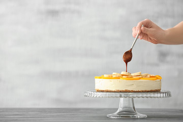 Female hand pouring chocolate on delicious cheesecake