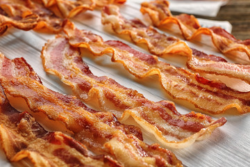 Wooden board with strips of fried bacon, closeup