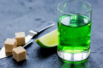 absinthe shots with lime slices and sugar on dark table background