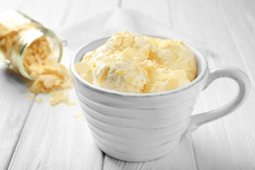Tasty ice-cream with almond slices in cup on wooden background