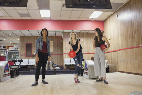 A young women bowling with friends.