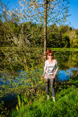Fototapeta na wymiar Femme au bord de l'étang de pêche au printemps 