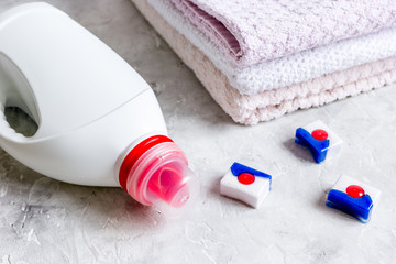 Pile of pastel towels with detergent in laundry stone background