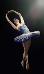 Young beautiful ballerina on dark background