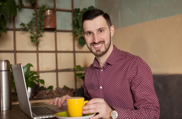 Shot of a young businessman working on his laptop in a cafe shop. Selective focus.