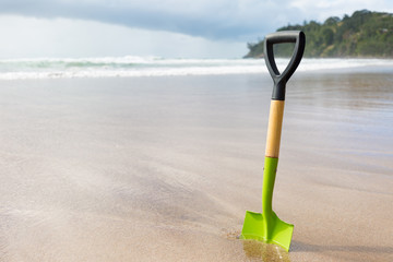 Spaten steckt im Sand am Meer