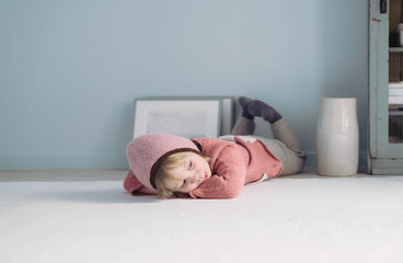 Müdes kleines Mädchen liegt auf dem Boden und ruht sich aus