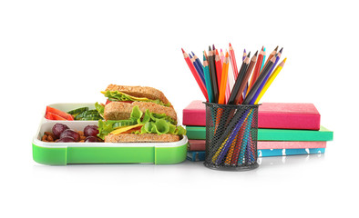 Lunch box with food and stationery on white background