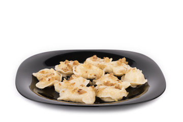 Fresh dumplings on a black plate seasoned with crispy onions. Ukraine