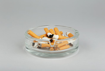 Cigarette butts in ashtray on light background
