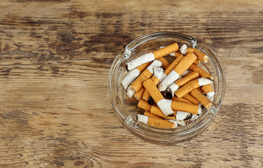 Cigarette butts in ashtray on wooden background