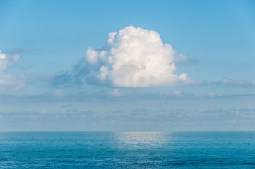 Naklejka premium Single cloud suspended in the sky over the ocean.