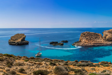 Fototapeta na wymiar Comino, Malta - Panoramic skyline view of the beautiful Blue Lagoon on the island of Comino with sailboats and tourists enjoying the mediterranean sea