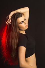 Naklejka premium Fashionable brunette woman with art makeup at studio with red light