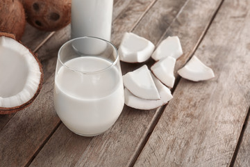 Glass of coconut milk with nuts on wooden background