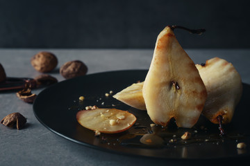 Plate with fried pears and walnuts on table