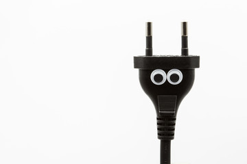 black electric plug with googly eyes on white background - close up