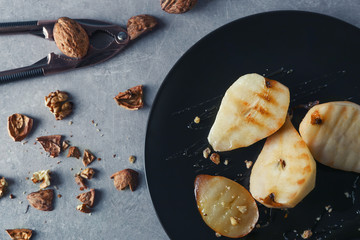 Plate with fried pears and walnuts on table
