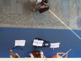 Female trio playing classical music on the street, bird's eye view, musicians only partially visible