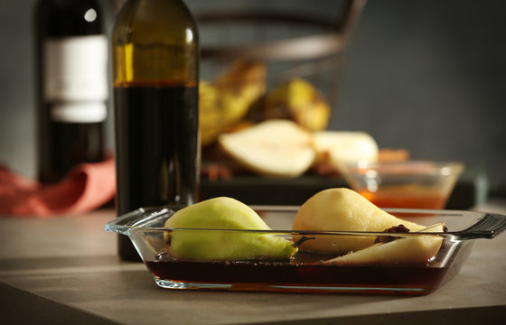 Pears with wine and spices in glass dish on table