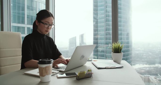 successful young Asian girl in a modern office skyscraper, the work environment, Steadicam shot