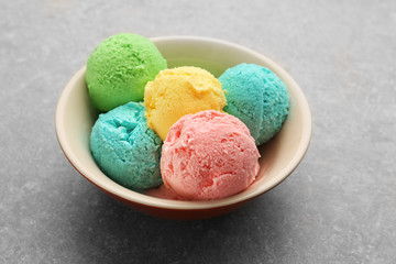 Bowl with different tasty ice cream  on gray background