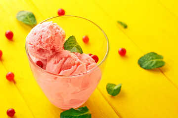 Tasty cranberry ice cream in glass on wooden background