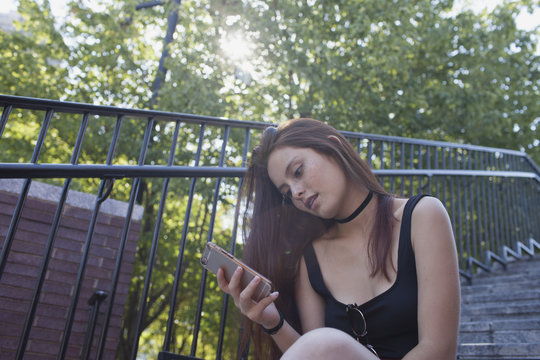 Young woman using cell phone while sitting on staircase