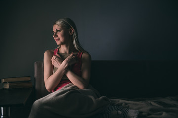 Girl enthusiastically reading a book best-selling house under a rug on a comfortable sofa with a lamp