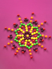 Colorful candies in shape of star on color background