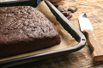 Baking tray with delicious chocolate cake on wooden table