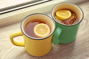 Cups of hot tea with lemon on window sill, closeup