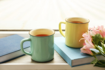 Composition with cups of hot tea on window sill