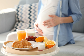 Obraz na płótnie Canvas Tray with healthy breakfast and blurred pregnant woman on background