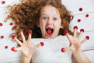 Angry child with raspberries on her fingers