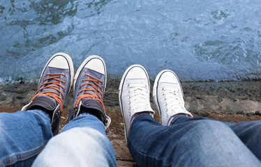 Couples feet resting on a river's edge. 