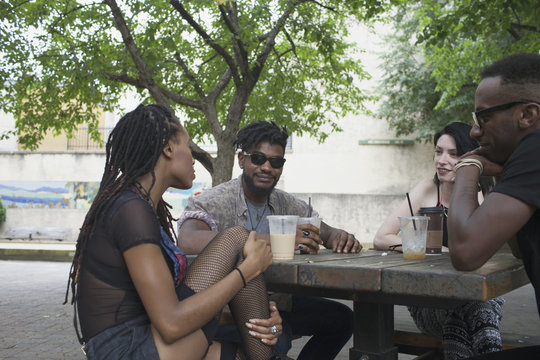 Friends talking with each other while sitting outdoors