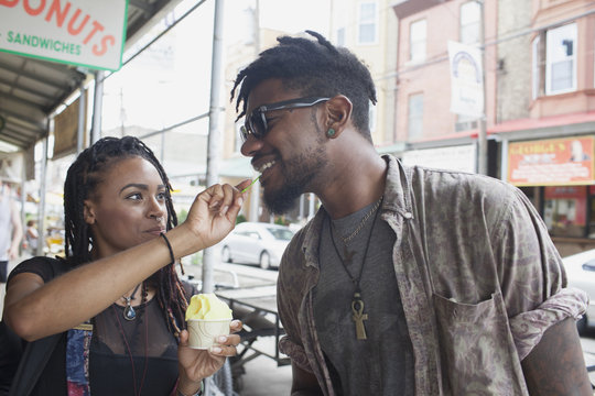 A young woman feeiding a young man frozen yoghurt.