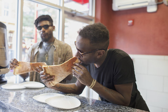 Two young men eating pizza.