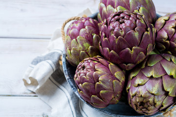 Fresh big Romanesco artichokes green-purple flower heads ready to cook