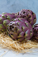 Fresh big Romanesco artichokes green-purple flower heads ready to cook