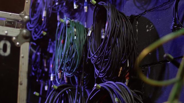 Electric cables for sound equipment are twisted hanging on the wall in the sound technician's office. Rock concert backstage wires and cables.