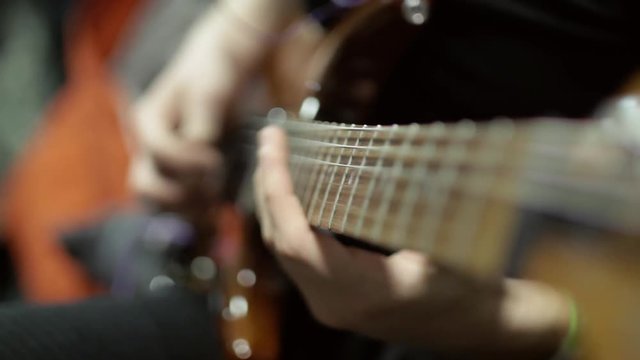 Playing an electric guitar warming before a large musical performance, live show. Men's hands are playing masterly on electric guitar, close-up.