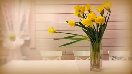  Bouquet of yellow daffodils in a vase on the table in the interior white. Filter: color focus. s